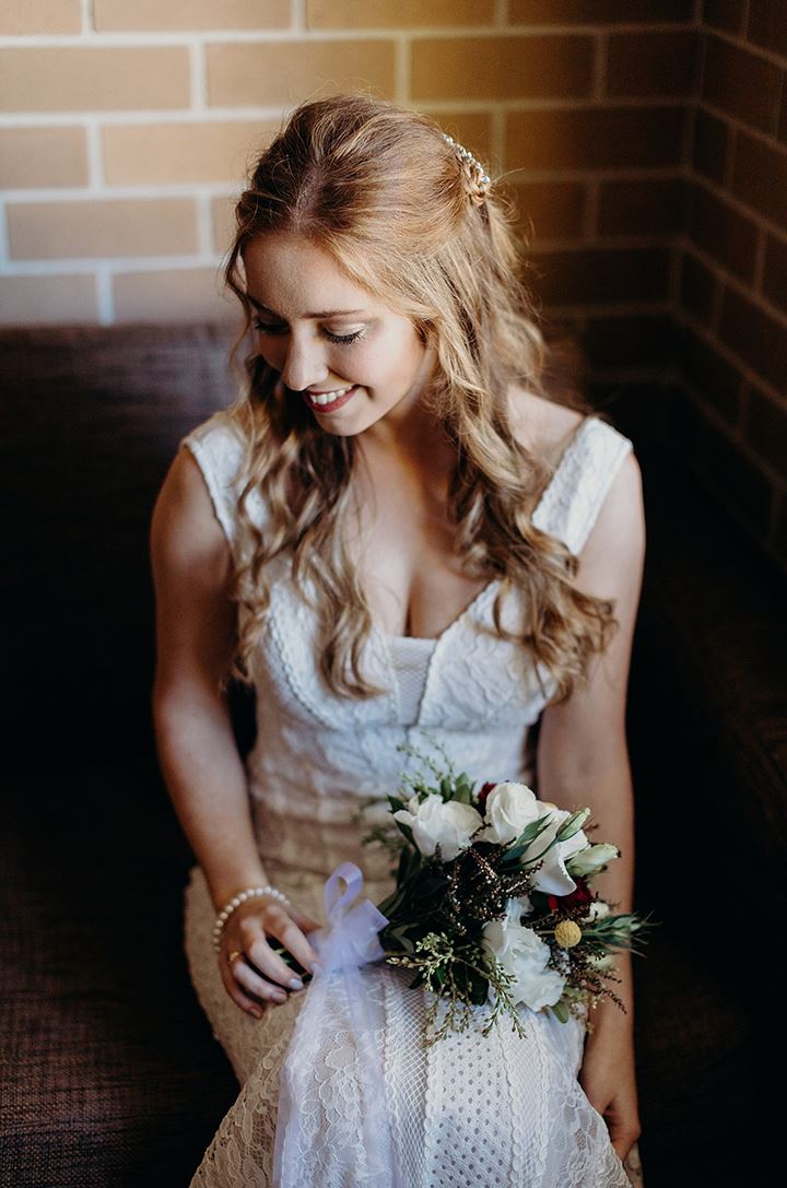 Bride smiling with a floral bouquet in lap