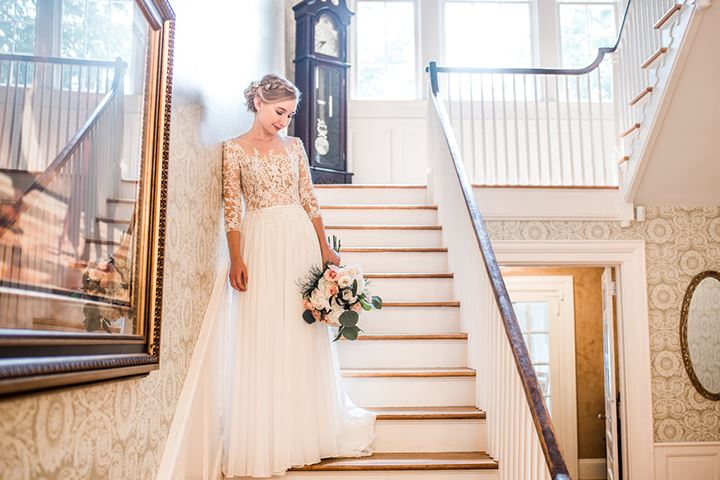 bride wearing lace wedding dress standing on stairs