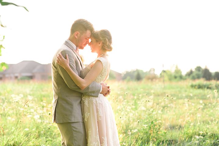 Bride and groom holding each other in a field