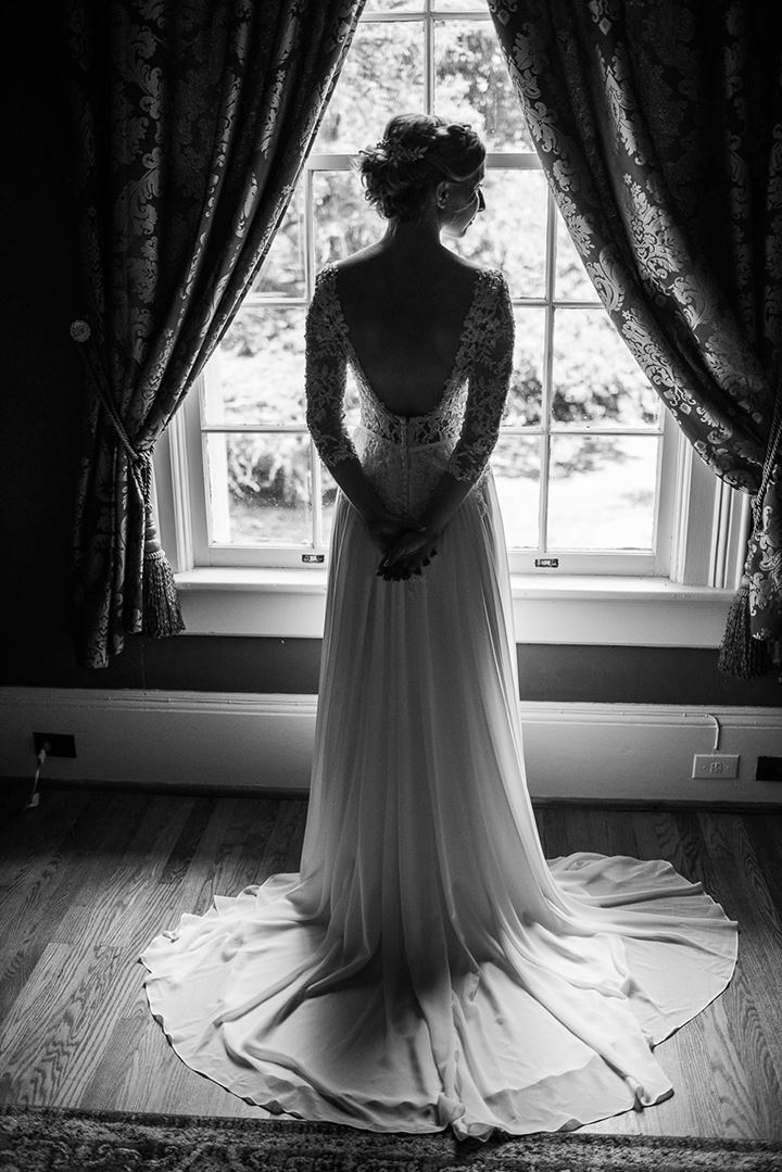 black and white image of bride standing in front of window