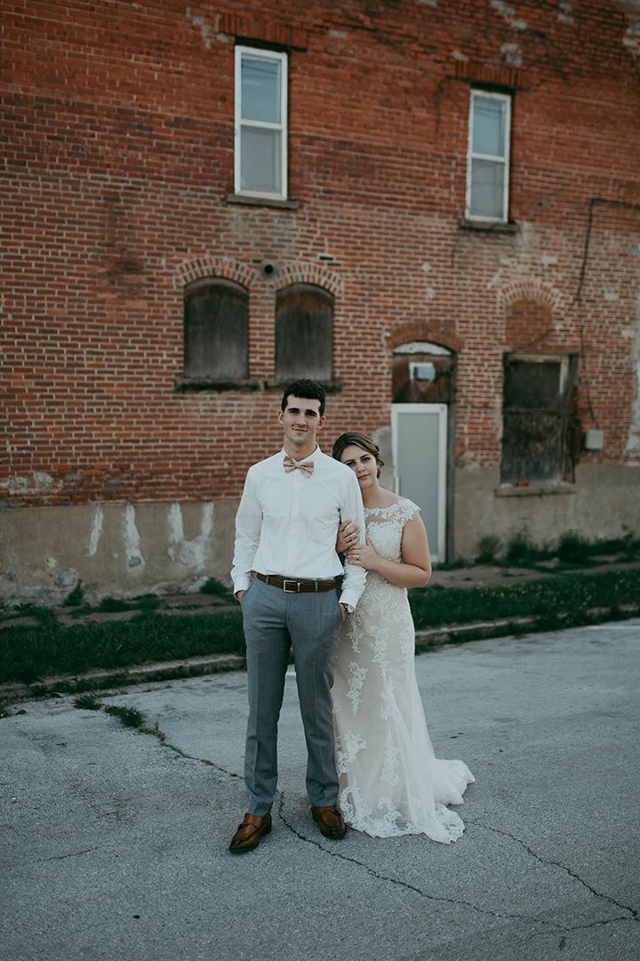 Bride and groom hugging each other in front of brick wall