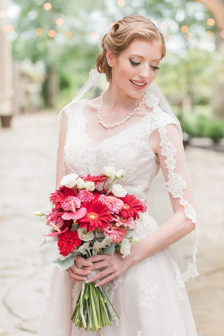 Bride posing with pink and red floral bouquet