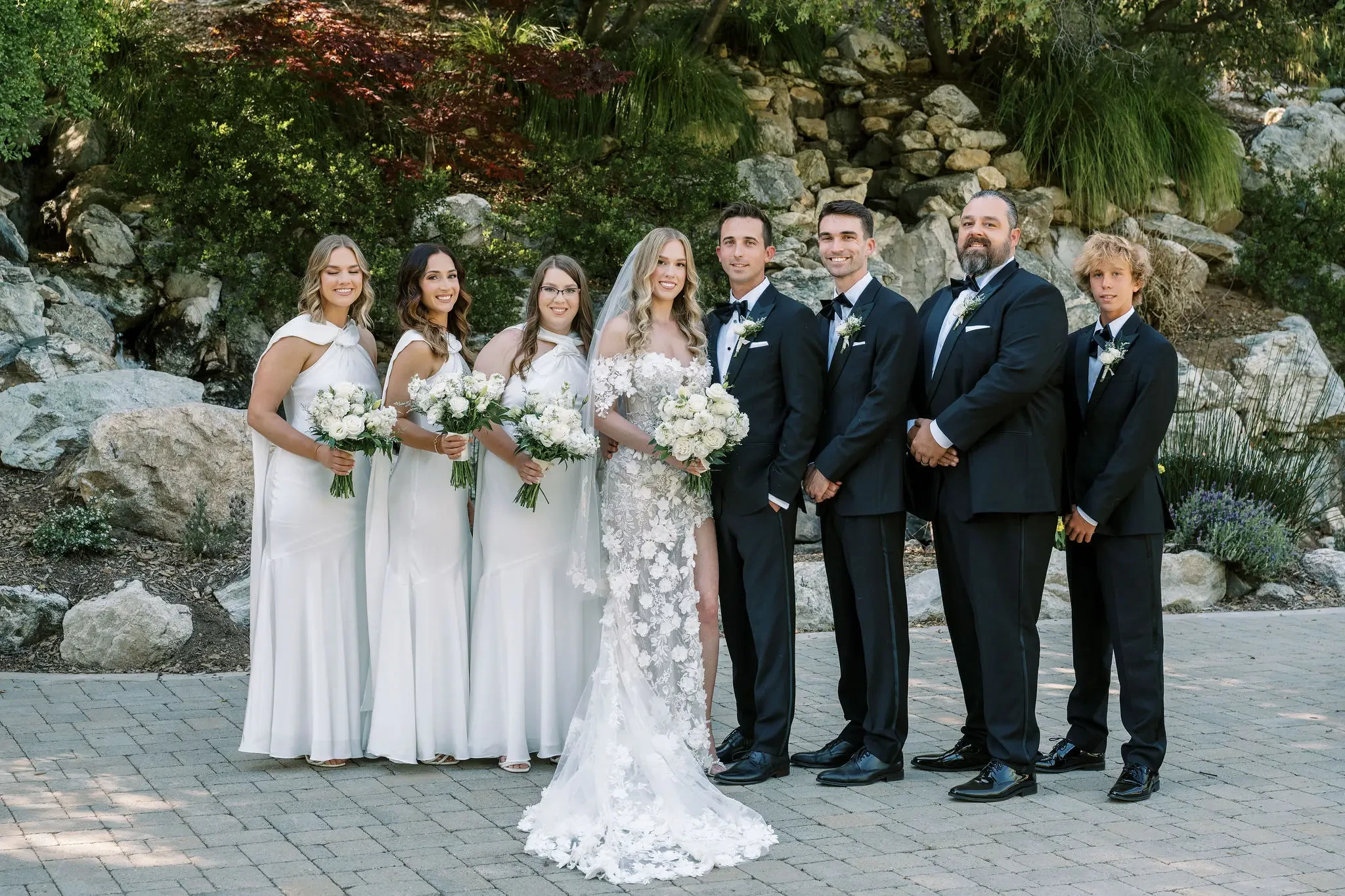 image shows bride and groom smiling with their bridal party and groomsmen