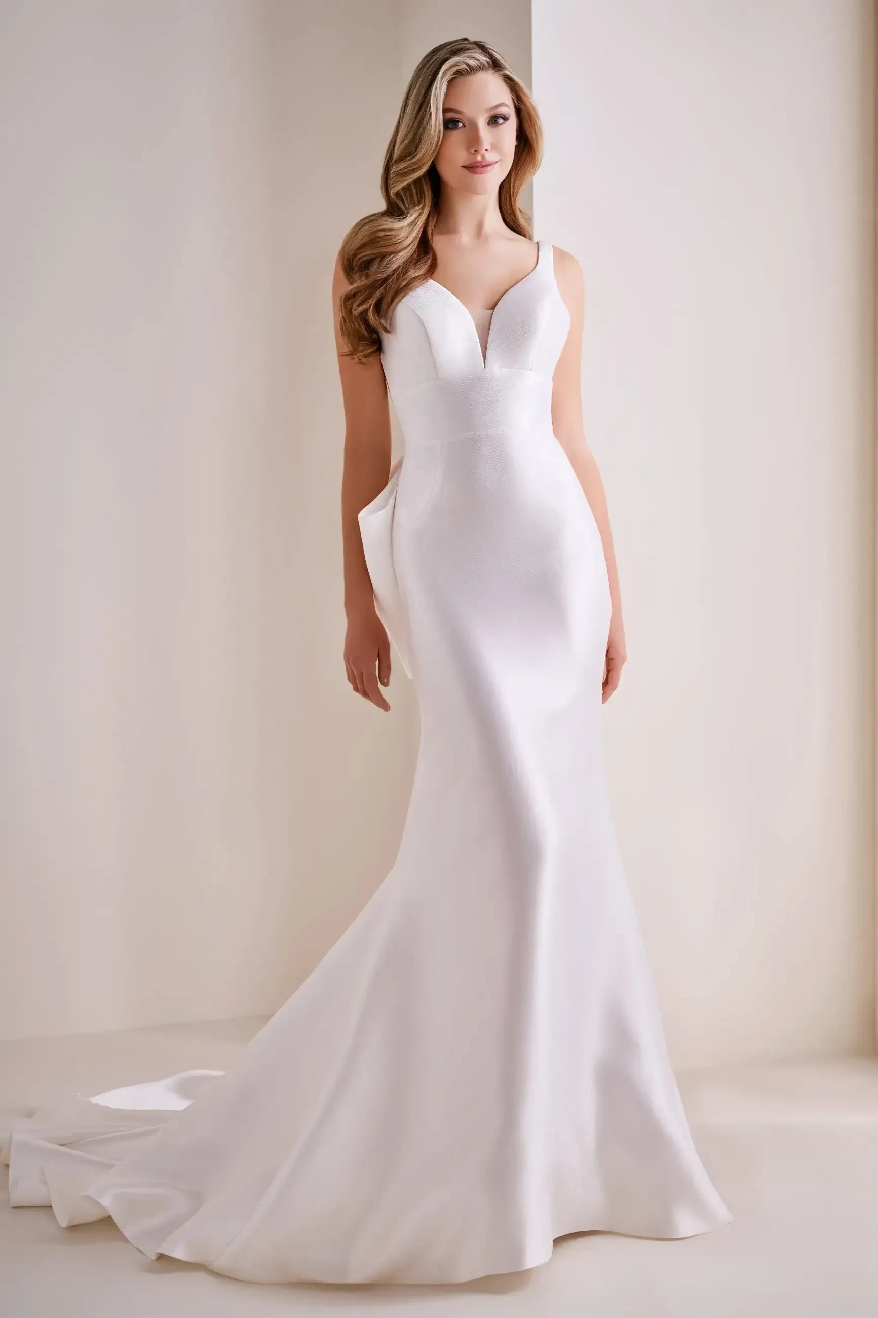 Model is wearing a sleek Mikado mermaid gown with a sweetheart neckline and a detachable oversized back bow.