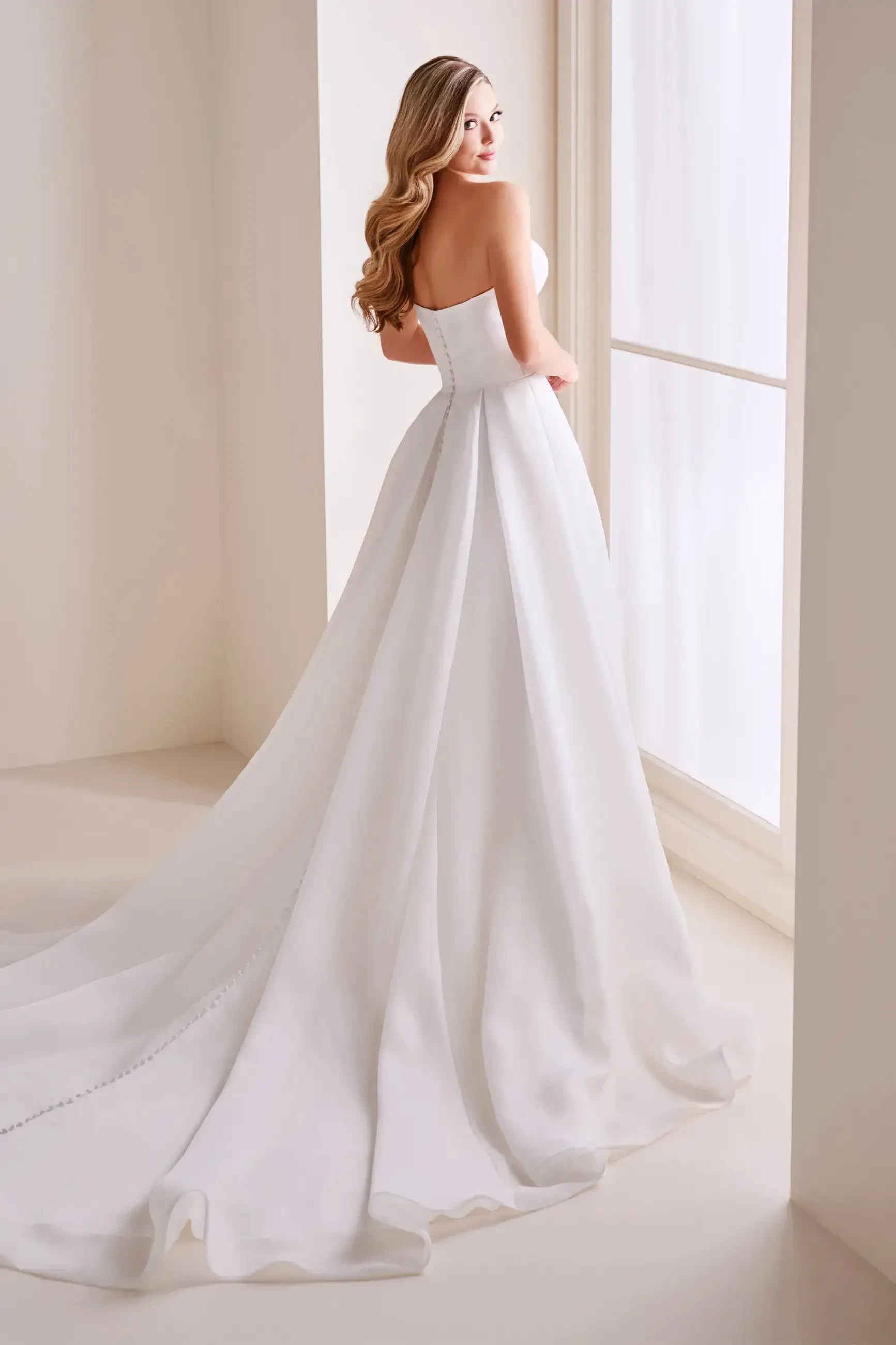 Model is wearing a strapless organza A-line wedding dress in ivory with a sculpted sweetheart neckline.