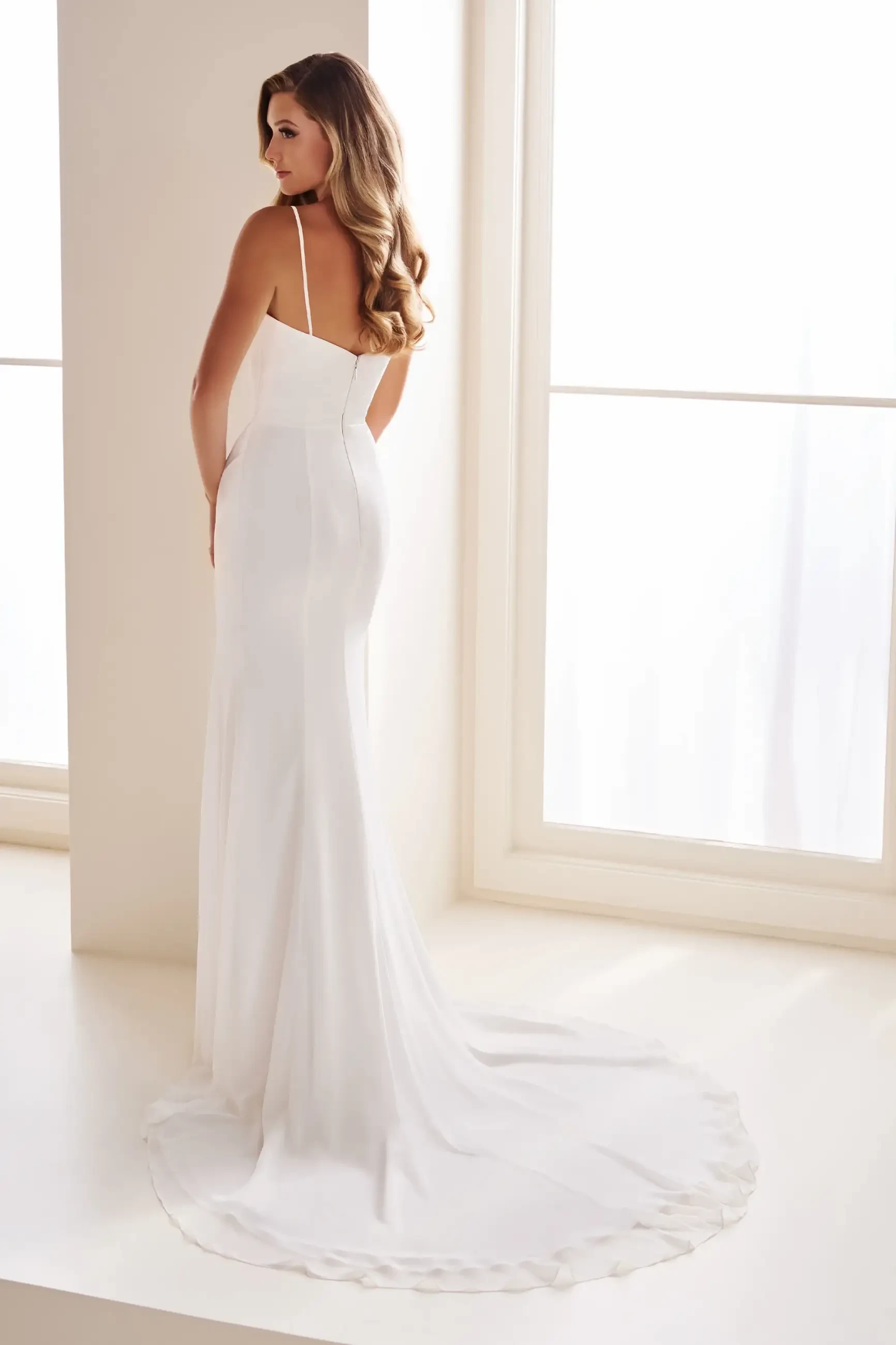 Model is wearing a fit-and-flare chiffon gown with a curved draped neckline, ruched waist, and satin lining.