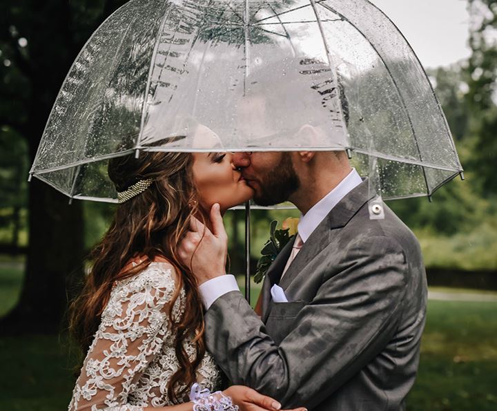 Bride and groom kissing in the rain