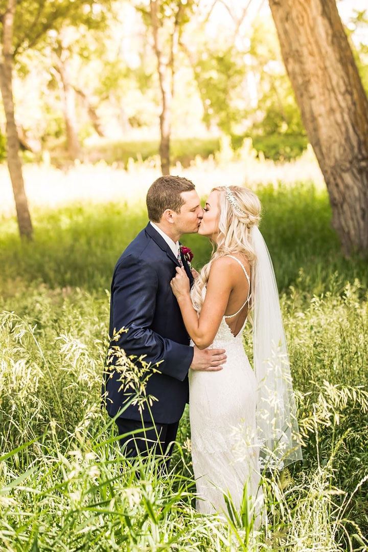 Bride and groom kissing in field