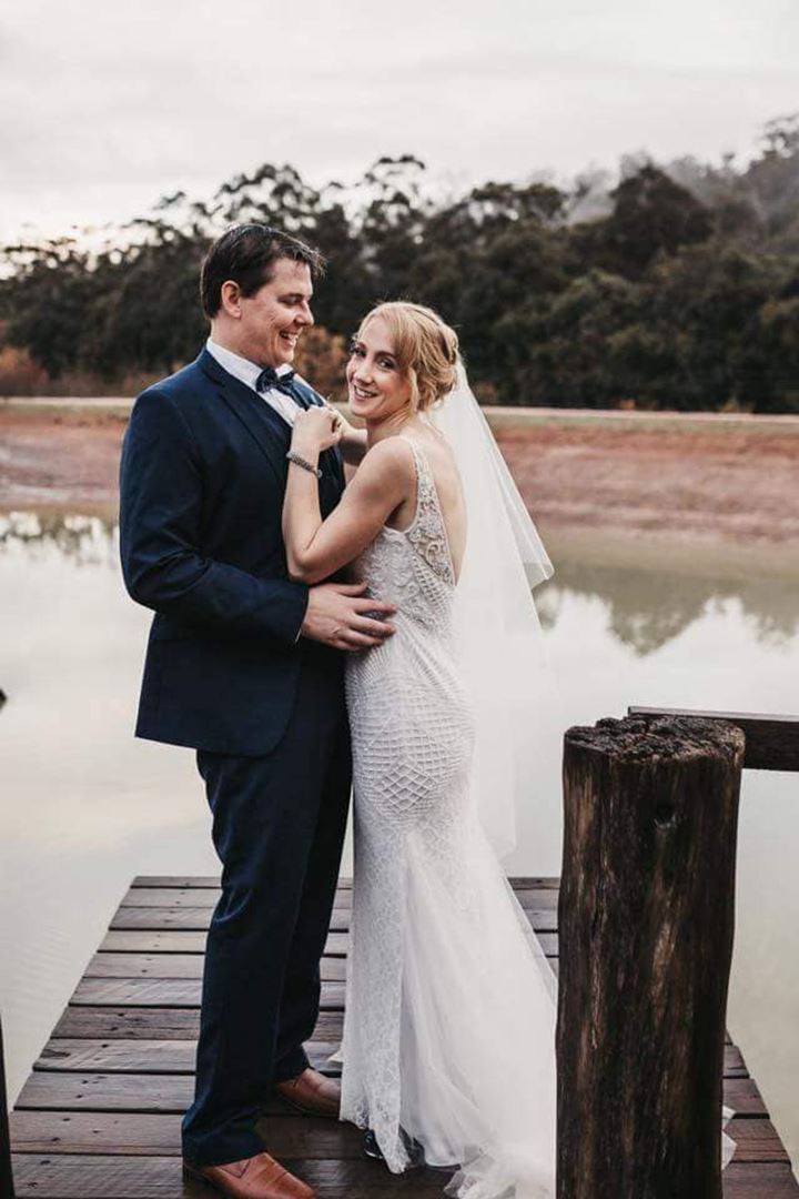 Bride and groom hugging each other in front of water